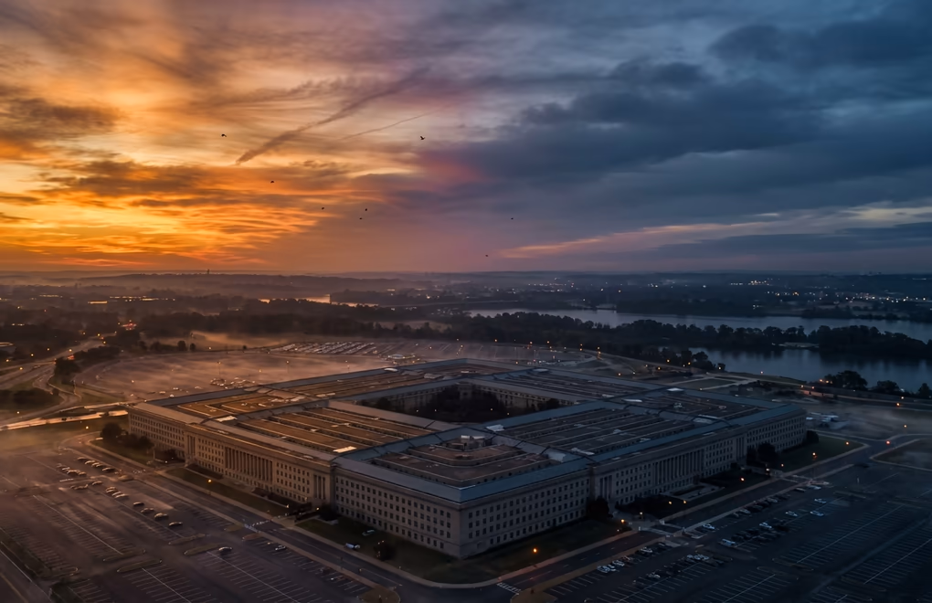 Dramatic overhead view of the Pentagon building at dusk with warm and cool light symbolizing the AI confrontation