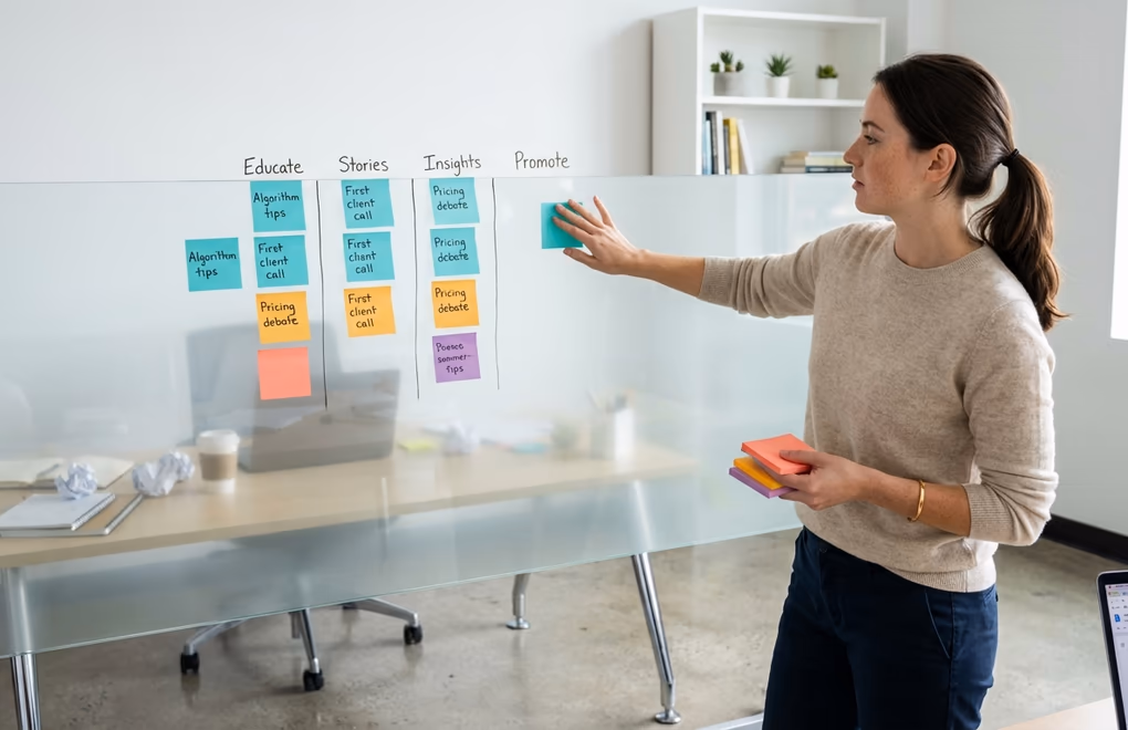 Person organizing colorful sticky notes on a glass wall representing planned LinkedIn content themes versus a messy desk with scattered papers