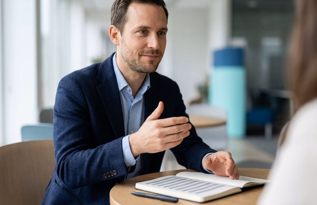 A seller nodding while actively listening across a small table during a sales meeting