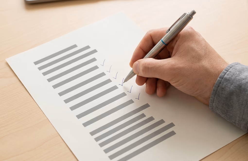 A hand checking off well matched prospects on a printed shortlist with a pen