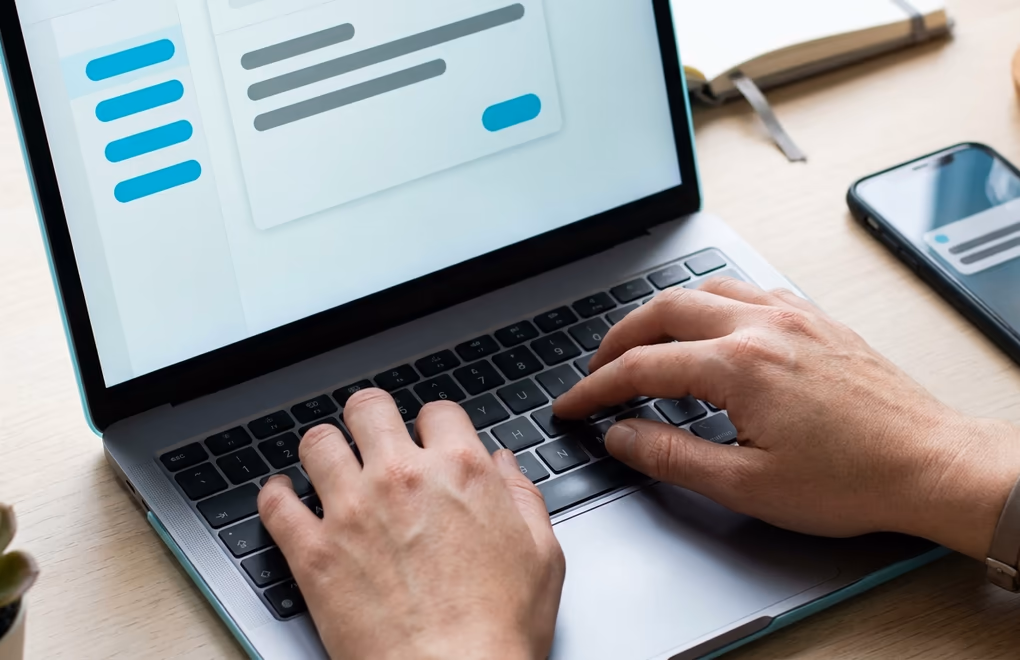 Hands typing a short personalized outreach message on a laptop next to a follow up schedule